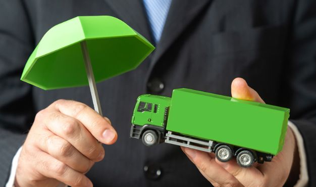 Green cargo truck protected by an umbrella, symbolising transport insurance and cargo risk protection.