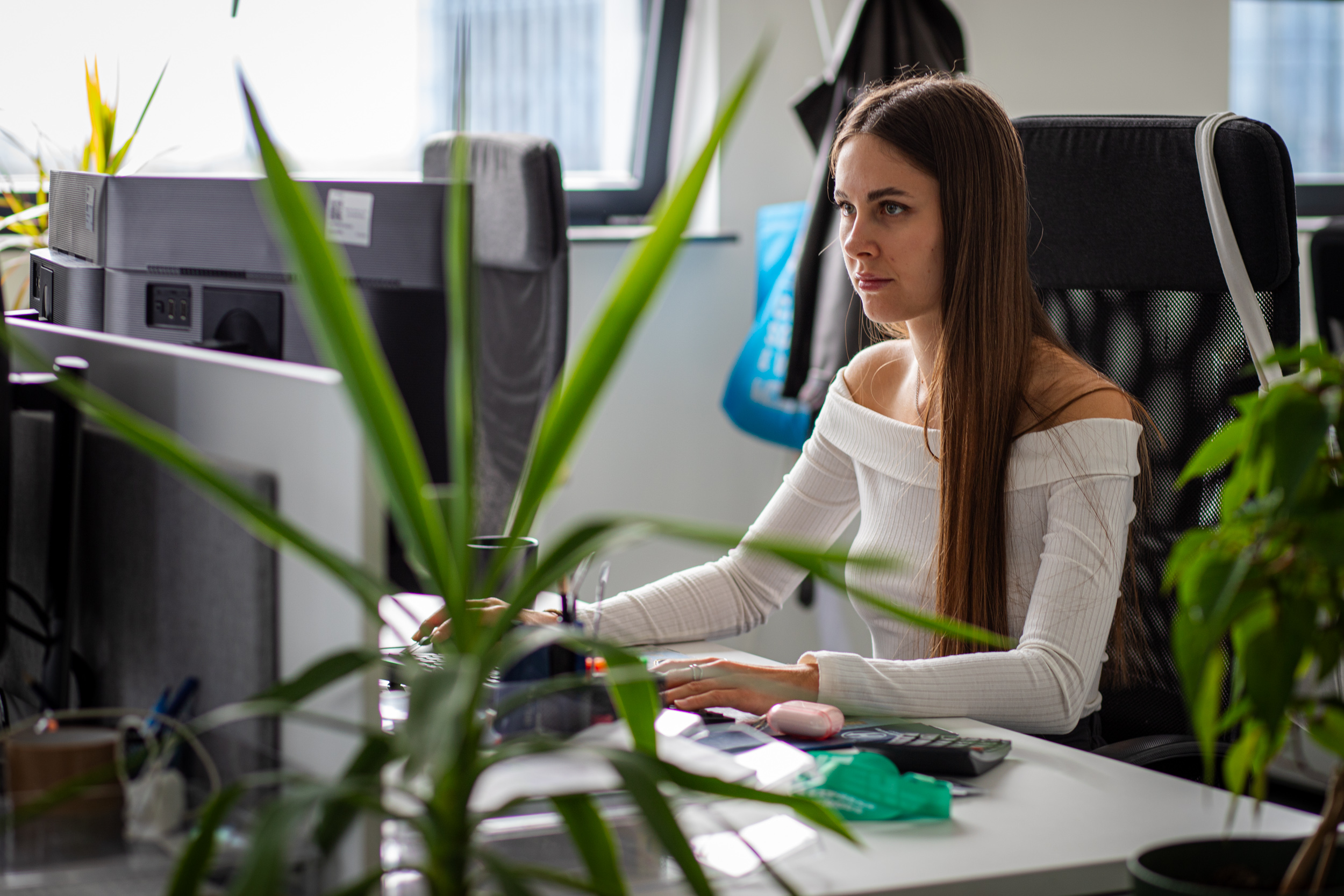 Express Heroes team member working at a computer, surrounded by plants in the Wrocław office.